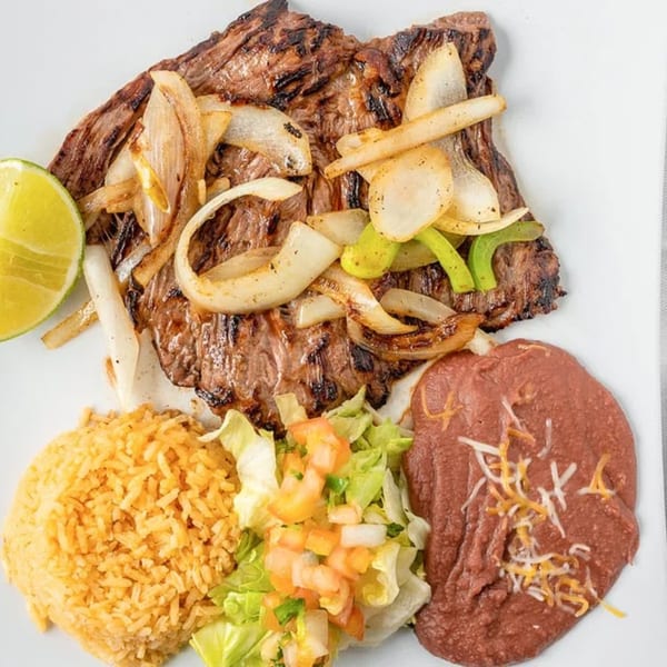 Grilled steak with onions and peppers, served with rice, refried beans, and a side salad.