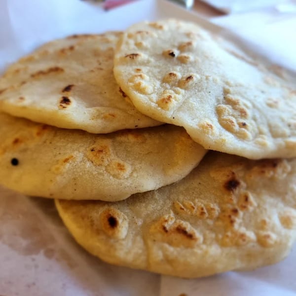 Close-up of a stack of warm, fluffy corn tortillas with lightly browned spots.