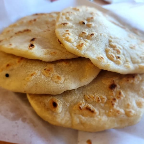 Close-up of a stack of warm, freshly made Mexican tortillas with light char marks.